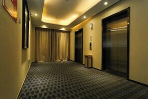 A hotel corridor with a patterned carpet, a closed elevator, and a door with a sign. - Lan'o Shangpin Hotel Xiangshuihua Never Sleeping City (Xiangshui)