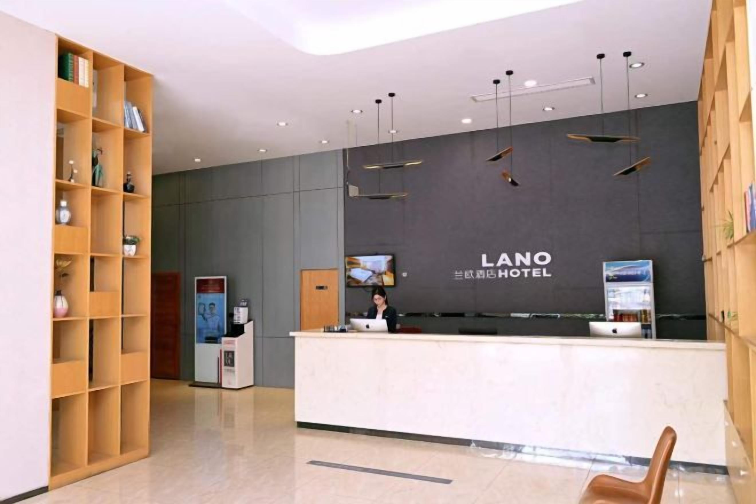 A hotel reception area with a reception desk, a TV screen, and a bookshelf.