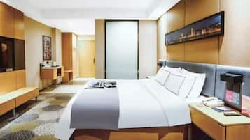A hotel room with a large bed, bedside table, and a desk with a chair.