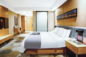 A hotel room with a large bed, bedside table, and a desk with a chair. - Lan'o Shangpin Hotel Xiangshuihua Never Sleeping City (Xiangshui)