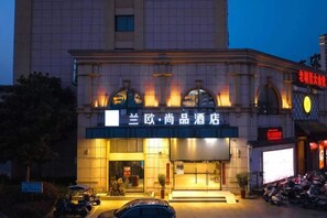 A hotel with a prominent sign, a gated entrance, and a parking area with motorcycles.