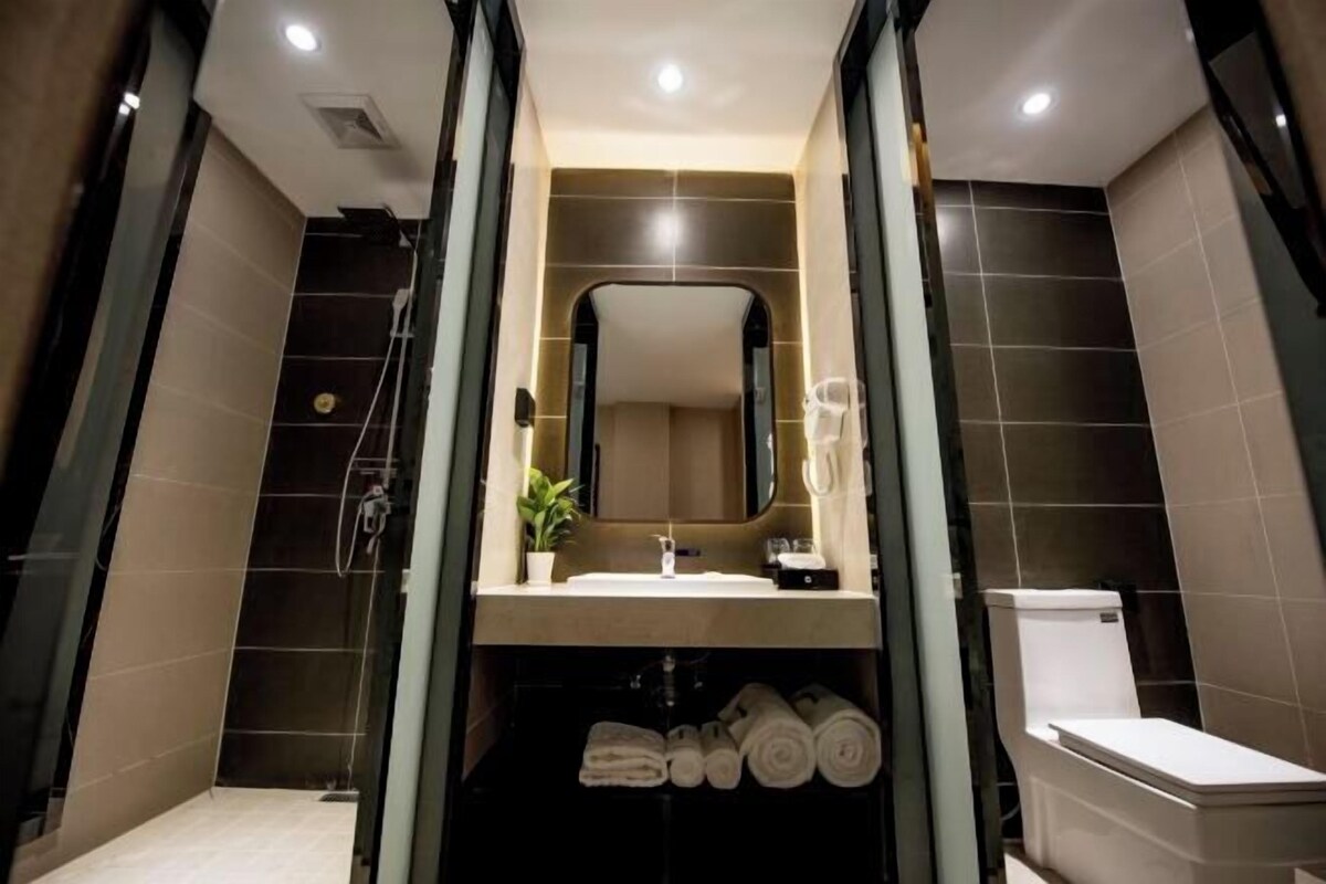 A modern bathroom with a glass shower enclosure, a sink with a mirror above, and a toilet.