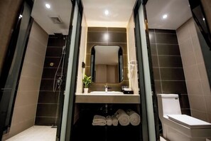 Ein modernes Badezimmer mit Duschkabine aus Glas, Waschbecken mit Spiegel darüber und Toilette.