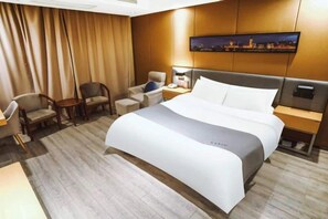 Una habitación de hotel con una cama grande, un escritorio, dos sillas, una mesita de noche y un cuadro en la pared.