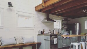 Een keuken met een houten bankje, een roestvrijstalen oven en een spoelbak.