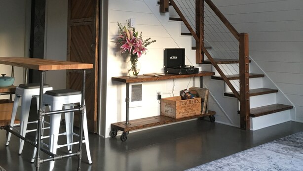 Een trap met houten leuningen, een bureau met een bloevas en een karretje met dozen.