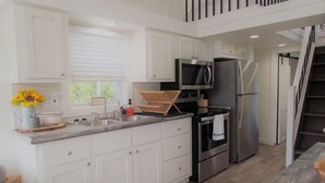 Une cuisine moderne avec des armoires blanches, des appareils en acier inoxydable et un plan de travail en bois.