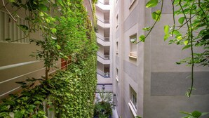 A narrow corridor with a lush green ivy-covered wall on one side and a plain building facade on the other.