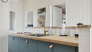 Una cucina moderna con un piano di lavoro in legno, un lavello e uno specchio sopra. Ci sono armadietti sotto il piano e una finestra sopra lo specchio.