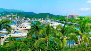 A marina with numerous boats docked, surrounded by lush greenery and palm trees. - Relax in front of Ixtapa's beautiful Marina. (Ixtapa Zihuatanejo)