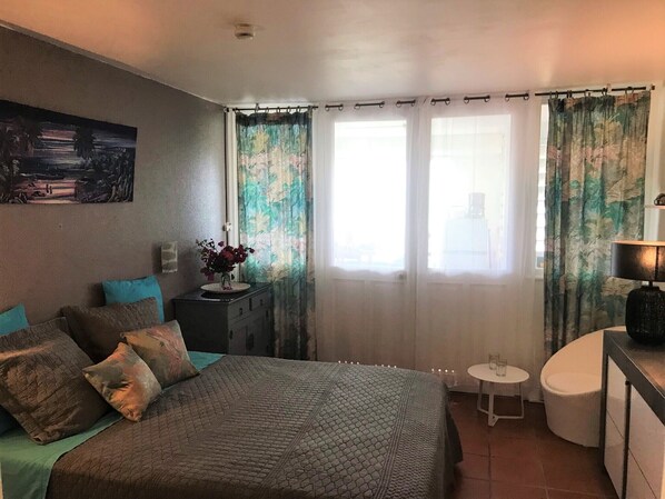 A bedroom with a bed, a dresser, a small table, and a lamp.