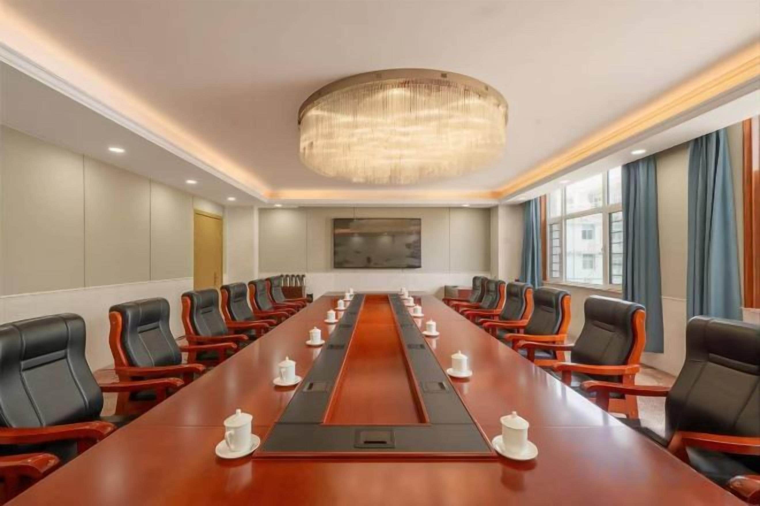 A conference room with a long table, multiple chairs, and a chandelier.