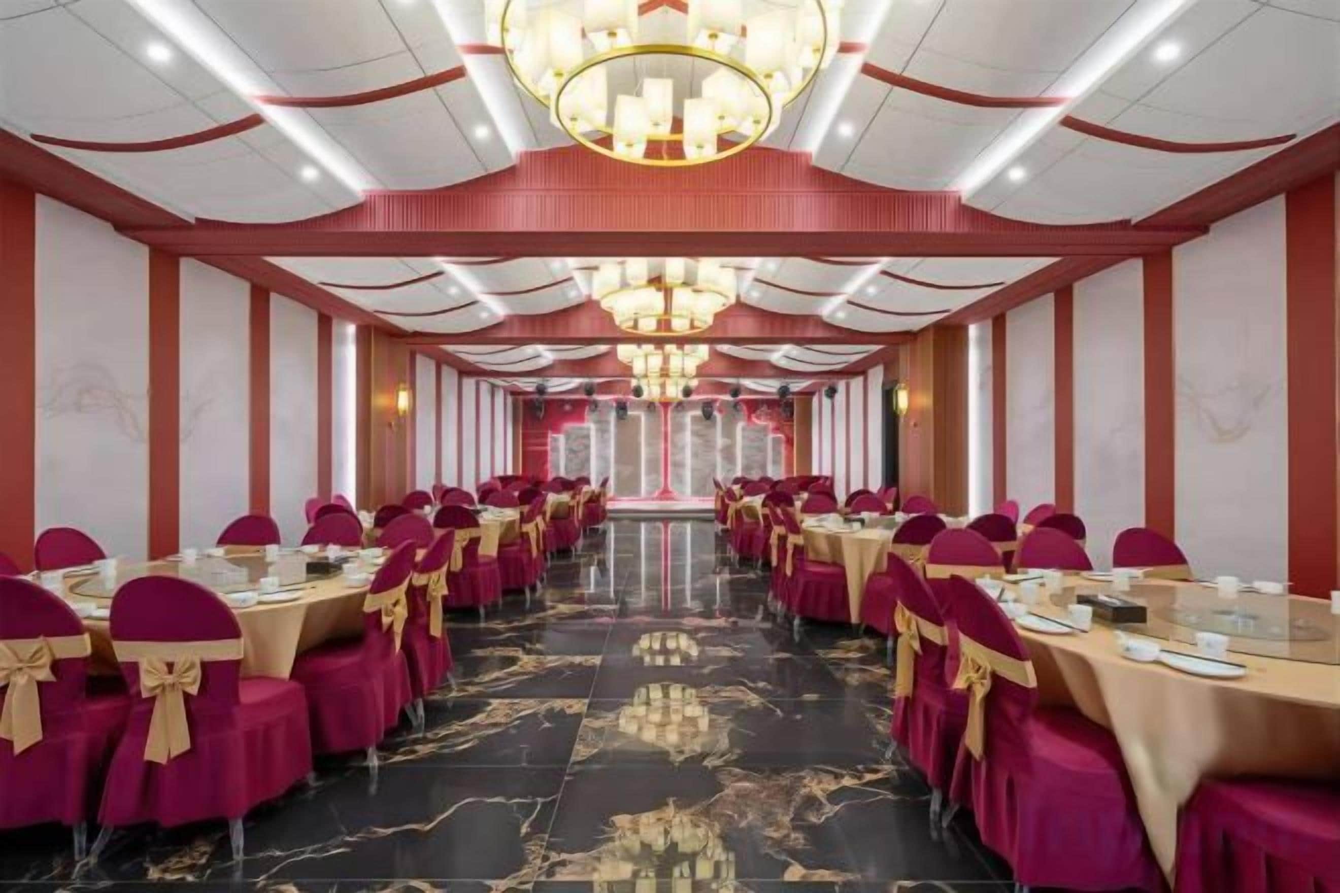A banquet hall with tables arranged in rows, a chandelier, and a marble floor.