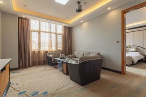 Una habitación de hotel con sofá, una mesita y una cama.