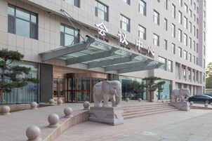 Un edificio moderno con entrada de cristal y dos estatuas de elefantes al frente.