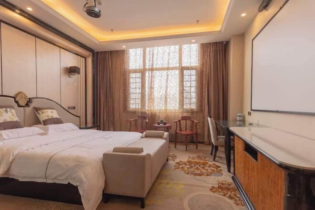 Una habitación de hotel con una cama grande, un escritorio y un ventanal con cortinas.