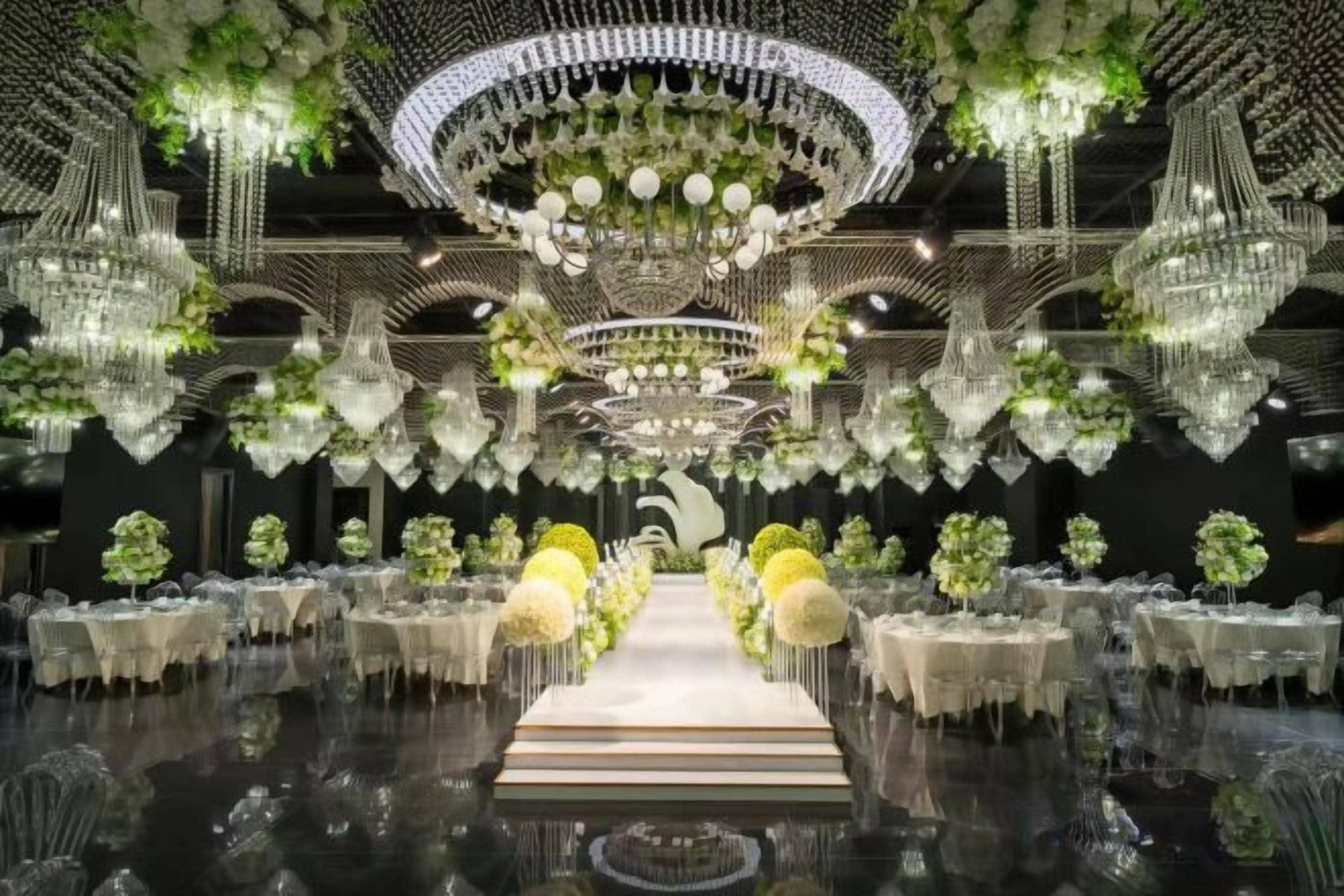 Ein prachtvoller Saal mit Kristalllüstern, einer zentralen Gänge und Tischen mit floralen Dekorationen.