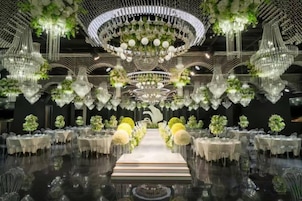 Un salón amplio con candelabros, un pasillo central y mesas adornadas con centros de flores.
