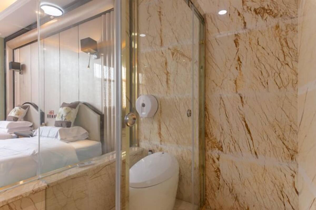 A modern bathroom with a glass shower enclosure, a marble wall, and a visible toilet.