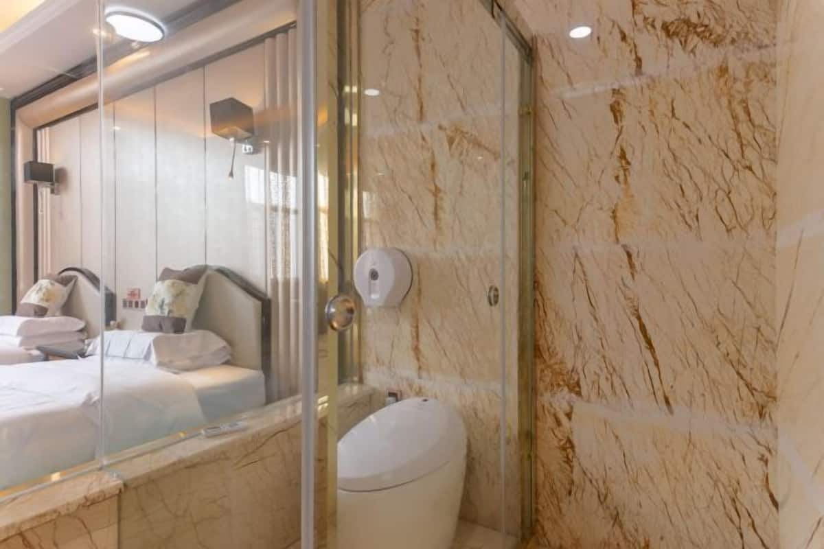 Un baño moderno con cabina de ducha de vidrio, pared de mármol y un inodoro a la vista.