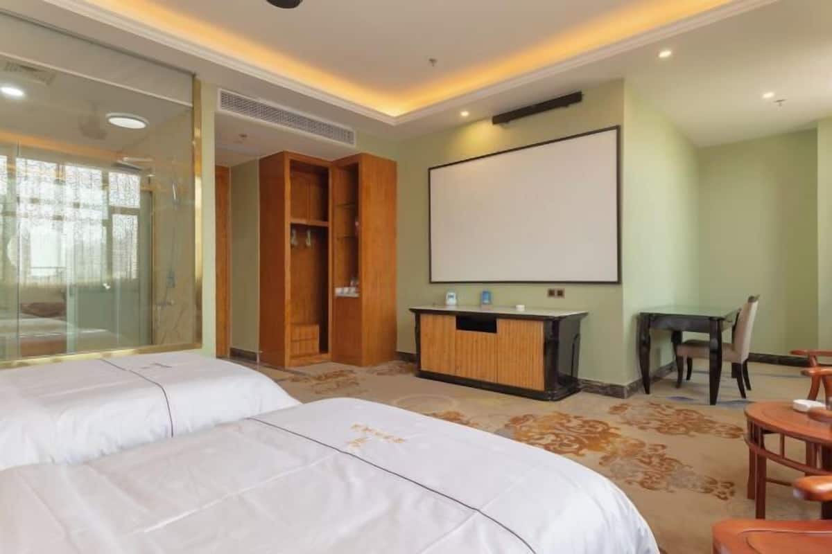 Habitación de hotel con dos camas, un escritorio, una silla, un televisor y un armario.