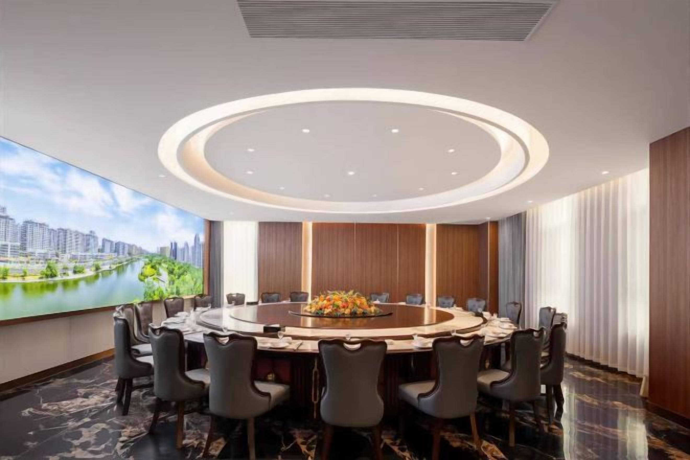 A conference room with a round table, chairs, and a cityscape view through the window.