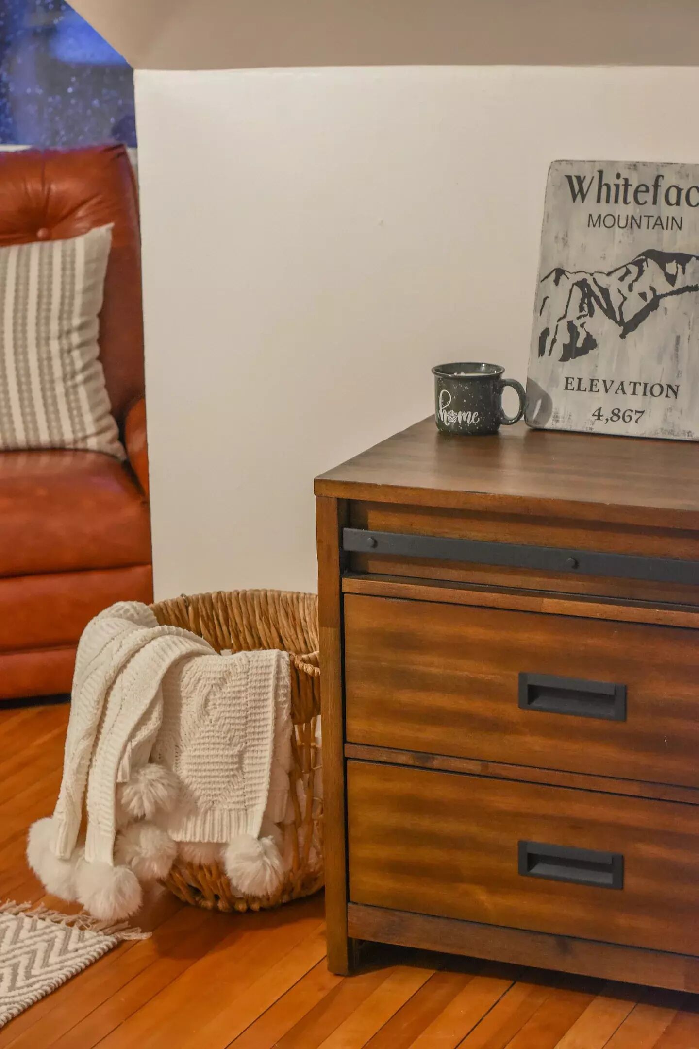 A wooden dresser with two drawers, a black mug, and a sign indicating the elevation of Whiteface Mountain.