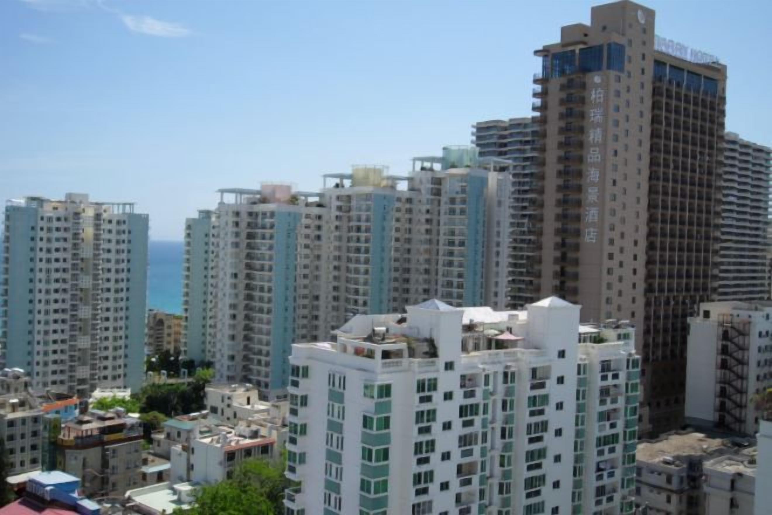 Un edificio residencial de gran altura con múltiples balcones, cielo despejado y vista al mar.