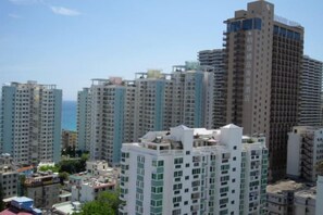 A high-rise residential building with multiple balconies, a clear sky, and a view of the sea. - Dadong Haiminghe Inn (Sanya)