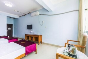 A hotel room with two beds, a television, a table with a kettle, and a chair. - Dadong Haiminghe Inn (Sanya)