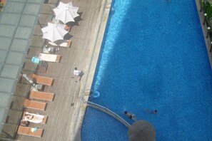 A swimming pool with lounge chairs and umbrellas, a covered seating area, and a poolside walkway. - Dadong Haiminghe Inn (Sanya)