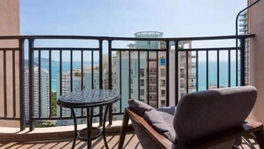 Ein Balkon mit Blick auf das Meer und Gebäude, ein runder Tisch und ein gepolsterter Stuhl.