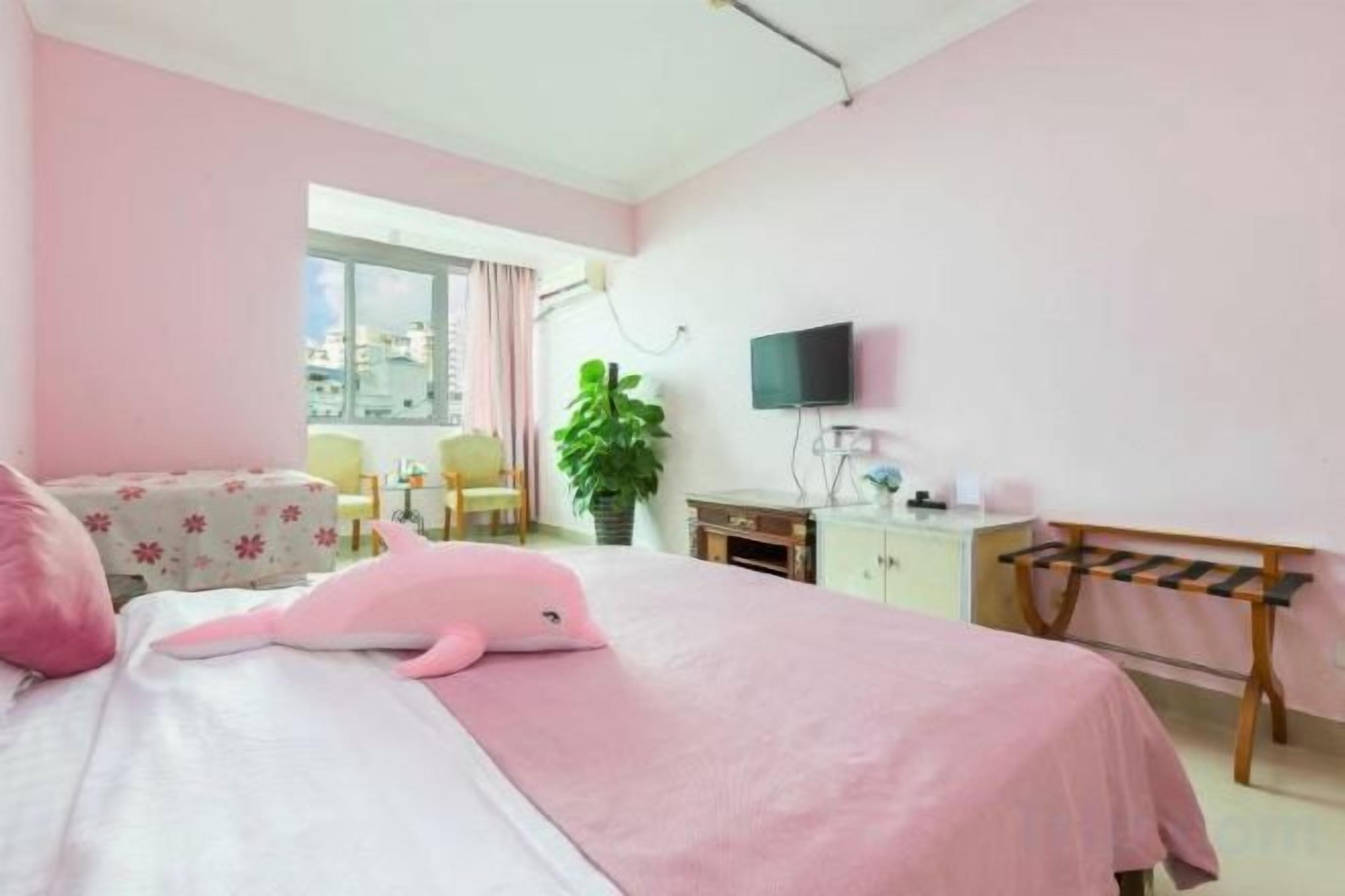 A hotel room with a bed, a desk, a chair, a television, and a balcony view.