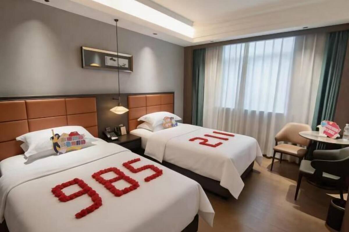 A hotel room with two beds, a desk, and a chair.