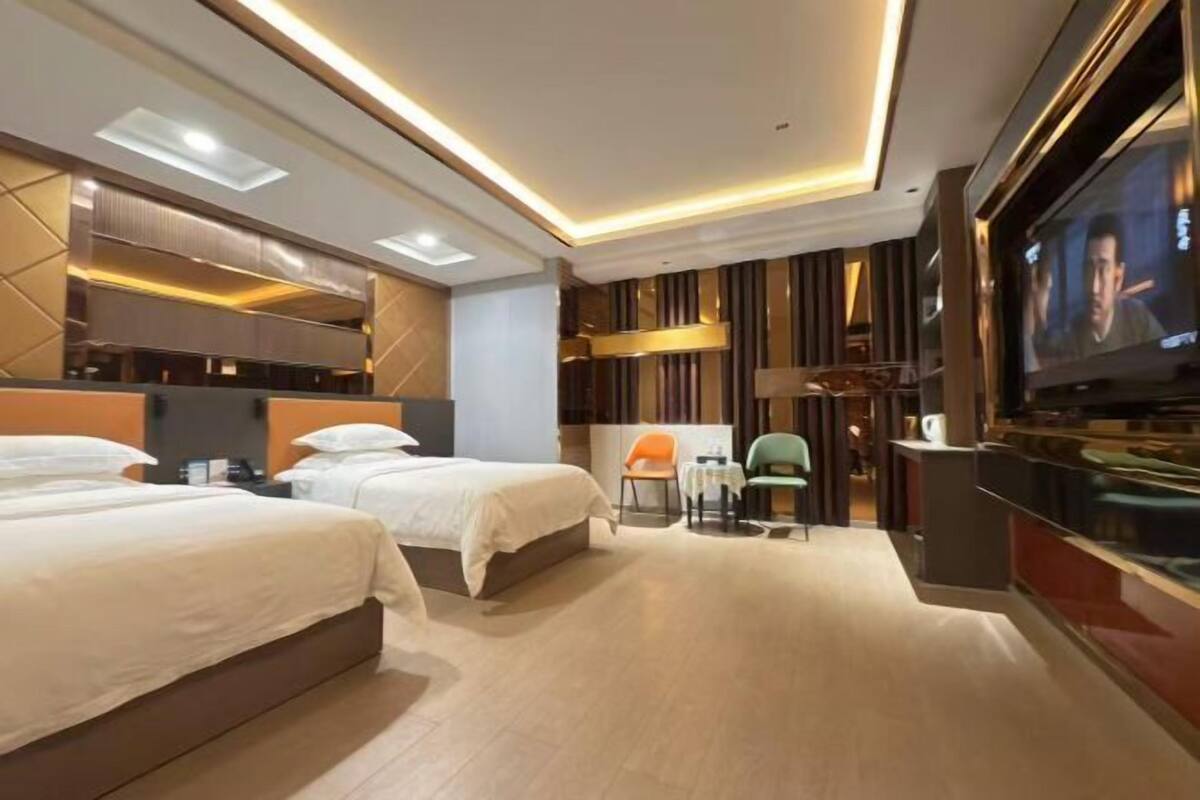 A modern hotel room with two beds, a TV, and a seating area with chairs and a table.