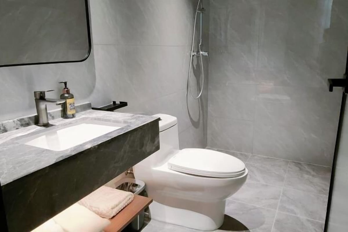 A modern bathroom with a marble sink, a toilet, and a shower.