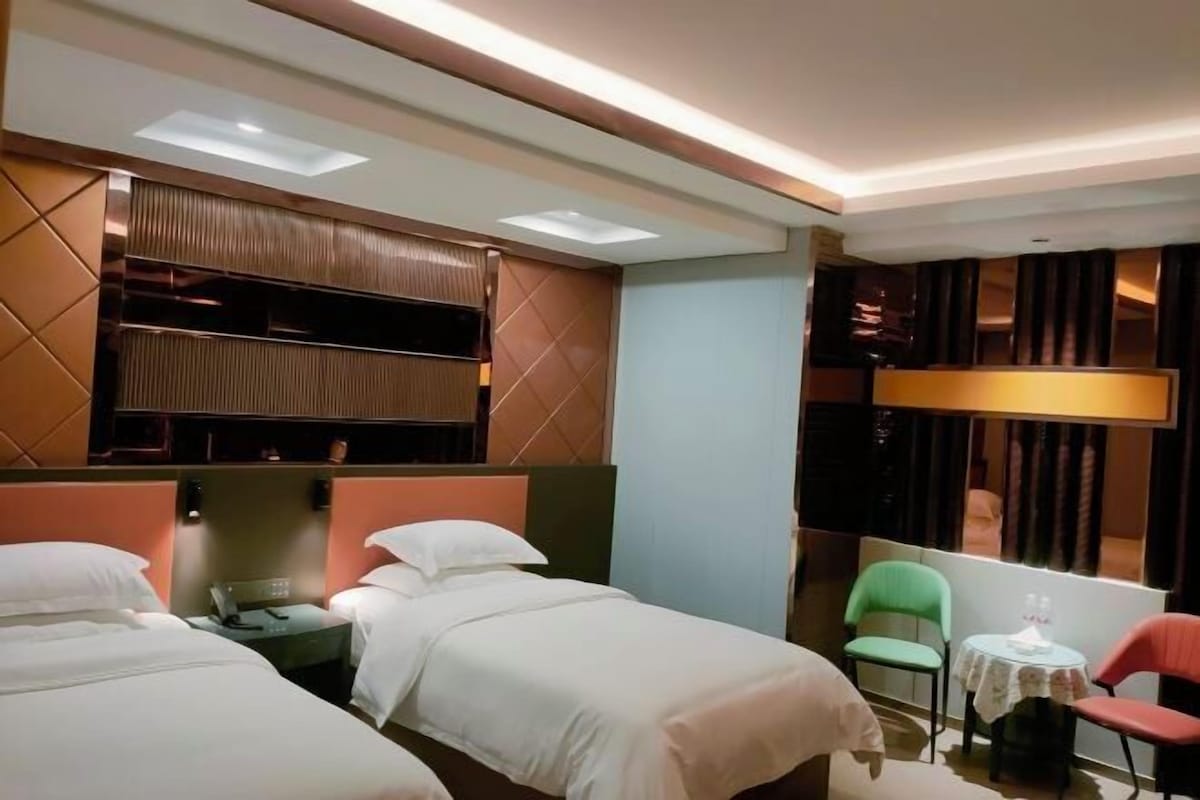A hotel room with two beds, a small table, a chair, and a sofa.
