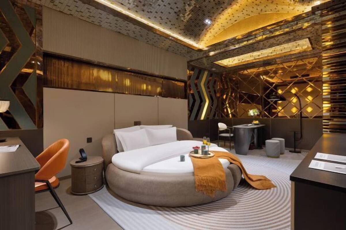 A modern hotel room with a circular bed, a desk, and a small seating area.