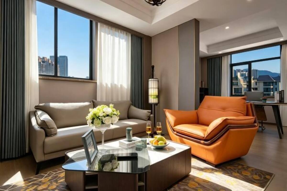 A modern hotel room with a sofa, armchair, and a coffee table.