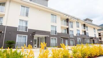 Un immeuble résidentiel moderne à plusieurs étages, doté de balcons, de grandes fenêtres et d’un toit plat.