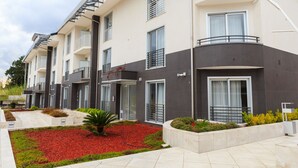 A modern multi-story building with balconies, large windows, and a landscaped garden area with red mulch and green plants. - Vignadonica Resort (Fisciano)