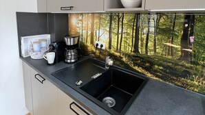 Una cocina moderna con encimera negra, electrodomésticos de acero inoxidable y un lavamanos.