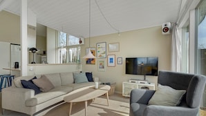A modern living room with a sofa, armchair, TV, and artwork on the wall. - Awesome home in Strøby with WiFi (Strøby)