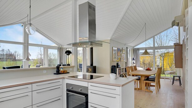 A modern kitchen with white cabinetry, a built-in oven, and a large island with a sink. - Awesome home in Strøby with WiFi (Strøby)