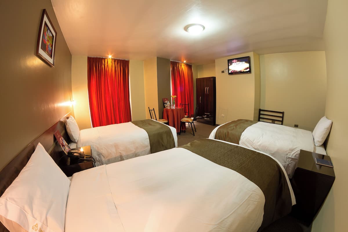 A hotel room with two beds, a desk, a chair, and a television.