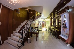 A hotel lobby with a staircase, a reception desk, and a bar area. - VILLA REAL UTASA (Puno)