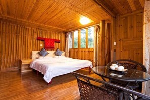 A wooden room with a bed, a table with a bowl of fruit, and a window. - Xiao Bei Lou (Longsheng)