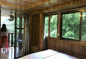 A wooden cabin with large windows, a bed, and a dining area. - Xiao Bei Lou (Longsheng)