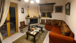 A living room with a fireplace, sofa, and a coffee table. - Αρχοντικό Δρυάδες 1 (Belokomiti)