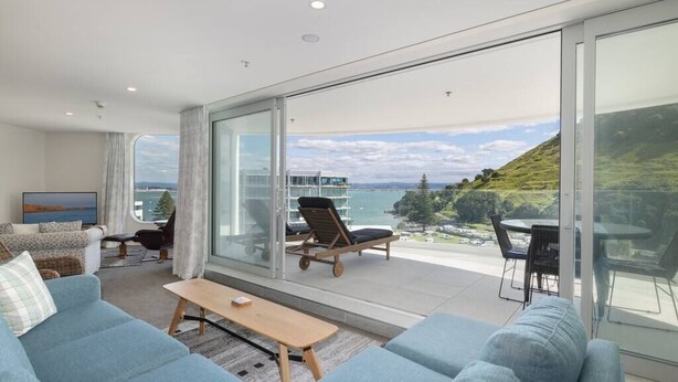 Ein modernes Wohnzimmer mit einer großen Schiebetür zu einem Balkon mit schöner Aussicht.